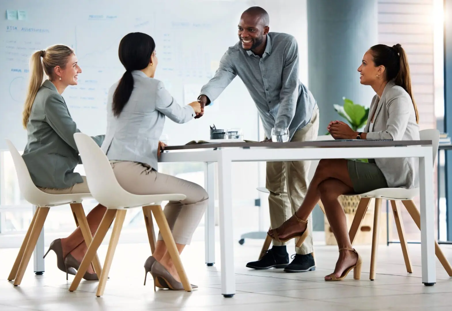 Business meeting with handshake and smiling colleagues.