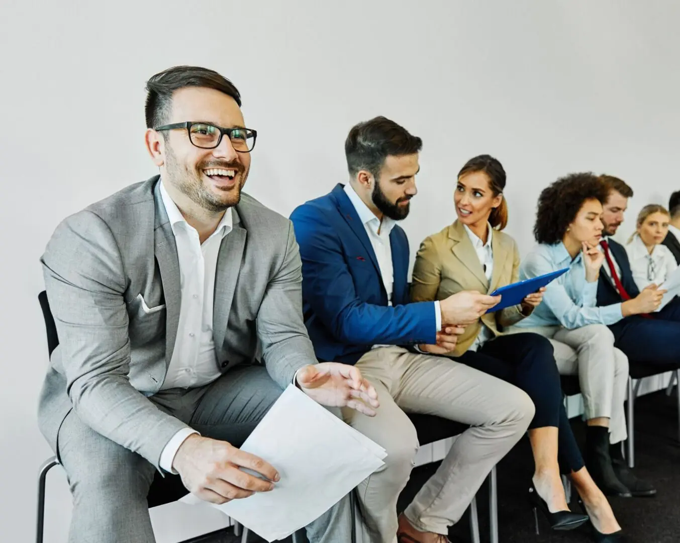 People sitting, talking, and holding documents.